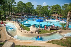 A water park with multiple pools, slides, and a large central pool area surrounded by trees. - Updated Townhome Blocks from the Beach! (Panama City Beach)
