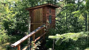 A wooden cabin with a wooden staircase leading up to it, surrounded by dense forest. - Off-Grid On Superior: Entire Private Cabin On Lake Superior (Hovland)