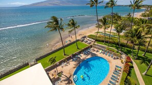 A resort with a swimming pool, beach, and palm trees.