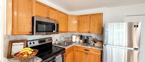A kitchen with wooden cabinets, a stainless steel refrigerator, a microwave, an oven, and a coffee maker.