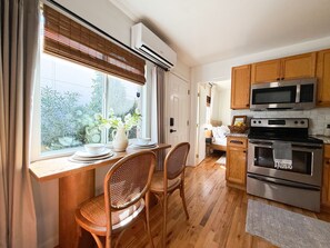 A kitchen with wooden cabinets, a microwave, an oven, and a dining area with a table and chairs.