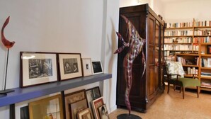 A room with a bookshelf, framed pictures, and a large sculpture.