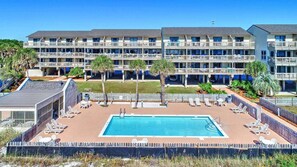 Un hotel con piscina, varios balcones y palmeras.