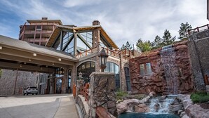 A modern building with a large glass facade, a stone exterior, and a waterfall feature. - Westgate 1BR, private patio, multiple pools, resort amenities, tennis, onsite spa, restaurant (Park City)