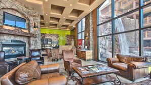 A spacious lobby with leather seating, a stone fireplace, a bar area, and large windows with a waterfall view. - Westgate 1BR, private patio, multiple pools, resort amenities, tennis, onsite spa, restaurant (Park City)