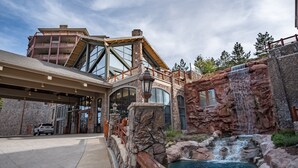 A modern building with a large glass entrance, a waterfall feature, and a stone facade. - Ski in/out at Westgate, studio, Resort amenities, Mutiple Pools, Onsite Spa and Restaurant 4802B (Park City)