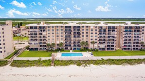 A multi-story hotel with a swimming pool, located near a beach. - Paradise in Ponce - Oceanfront 2BR Condo (Ponce Inlet)