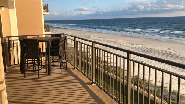 A balcony with a table and chairs overlooking a beach. - Paradise in Ponce - Oceanfront 2BR Condo (Ponce Inlet)