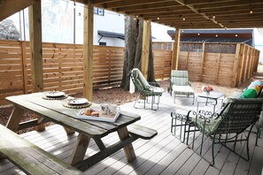 Relax on the patio with a picnic table, two comfortable chairs, and a charming table setting.