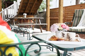 A patio area with outdoor furniture, including a table with a tray of pastries and a vase of flowers.
