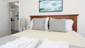 Una camera d'albergo con un letto grande, due cuscini decorati, un quadro incorniciato sopra il letto e un asciugamano piegato con cura sul letto.