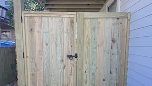Ett trähus med en svart hasp på dörren, placerat intill ett hus med träpanel.