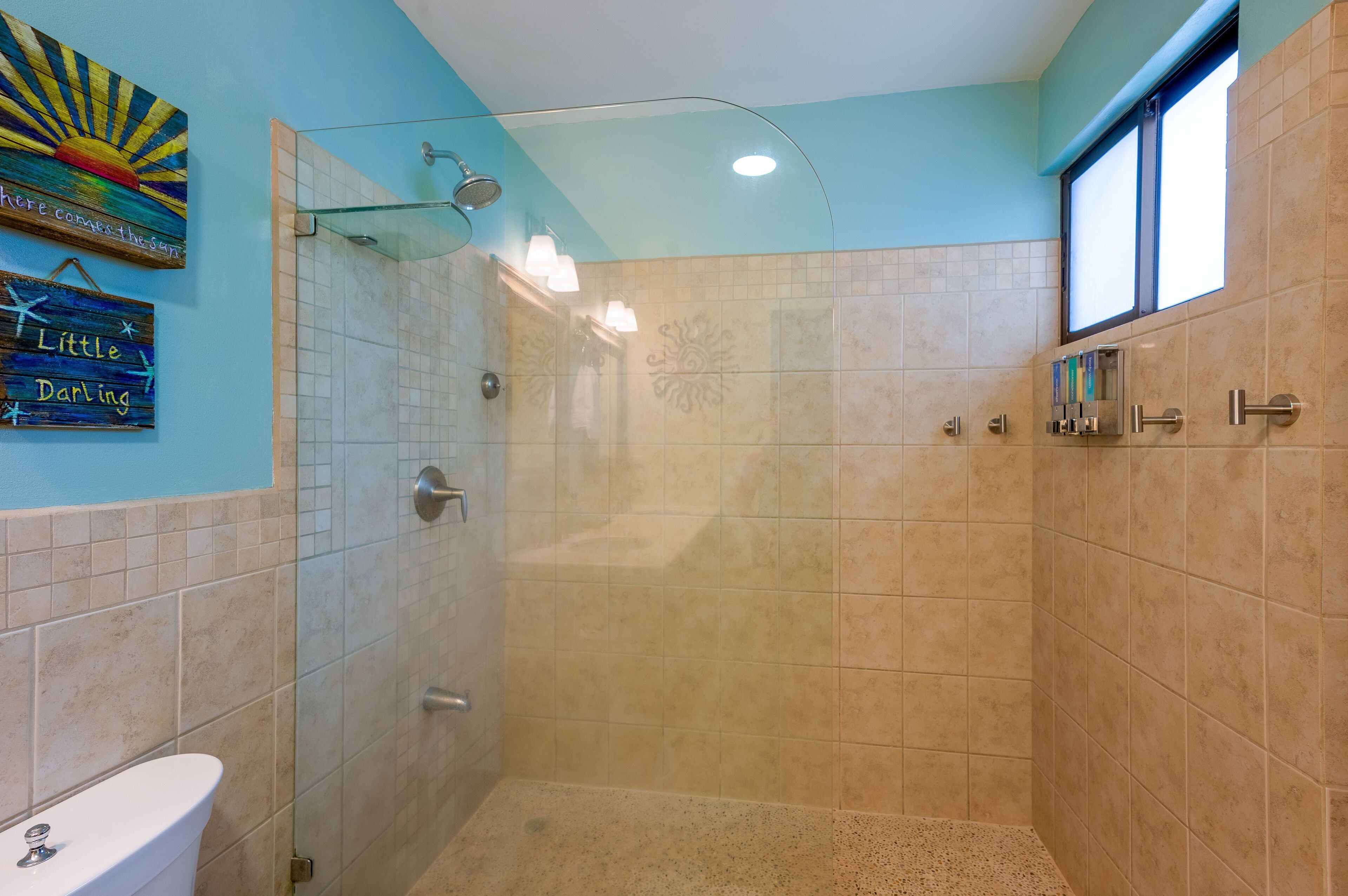 Une salle de bain équipée d’une douche, de toilettes et agrémentée d’œuvres d’art décoratives sur les murs.