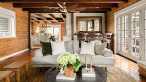 A log cabin interior with a sofa, coffee table, and a ceiling fan. - Chateau Syrah by AvantStay | Picturesque Estate w/ Pool, Pickleball, Hot Tub (Temecula)