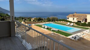 A pool with lounge chairs, a view of the sea, and a building with a tiled roof. - Apt Perterrepermari a 2 Km Da Riserva Dello Zingaro (Castellammare del Golfo)