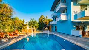 Une piscine avec des chaises longues et un bâtiment moderne doté de balcons.