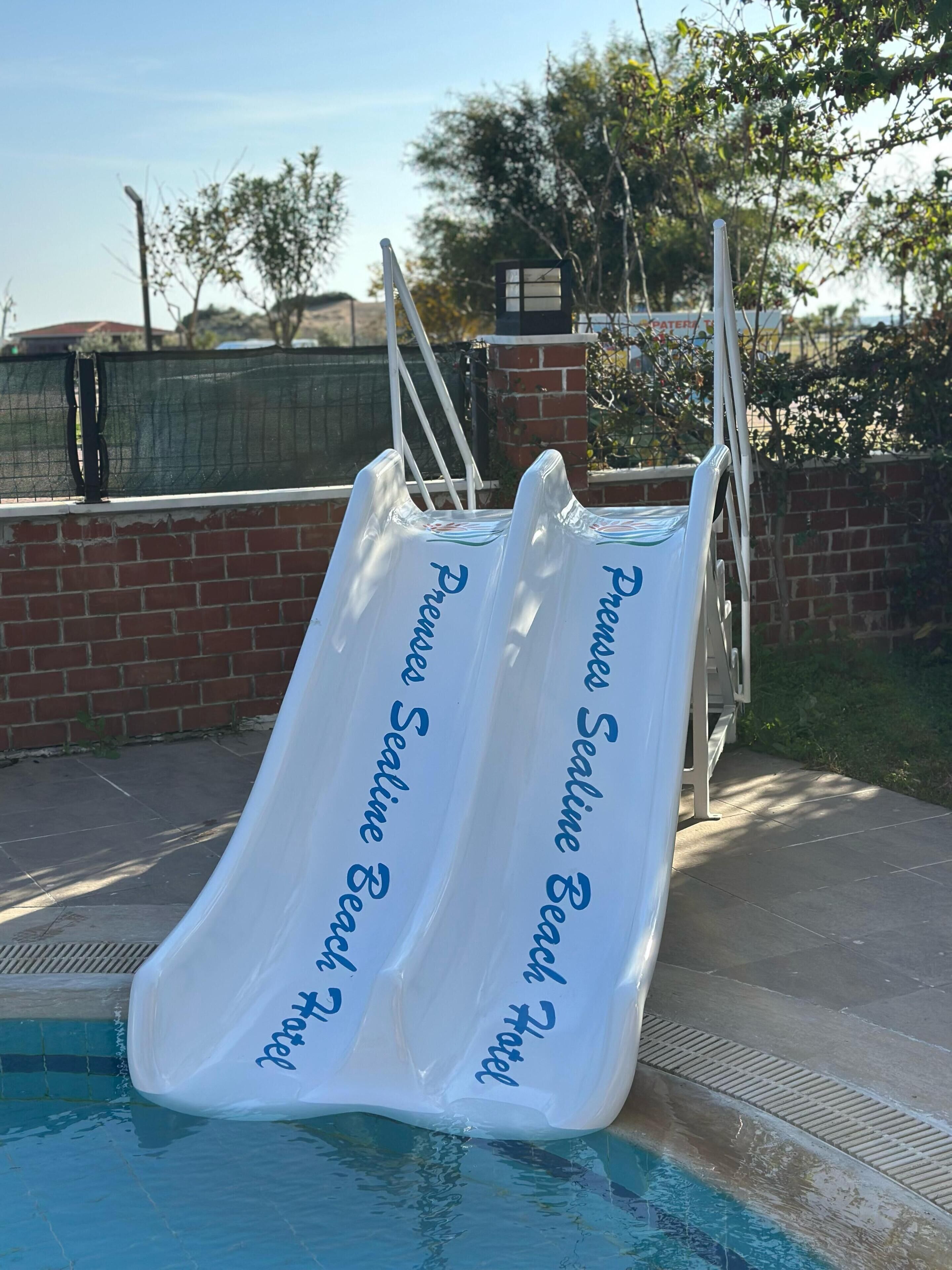 A pool with two white slides labeled "Premier Seaside Beach Hotel."