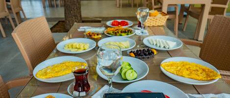 A dining table set with plates of food, including omelets and vegetables, and a glass of water.