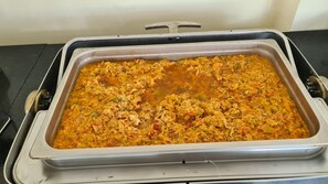 A large metal tray filled with a dish containing vegetables and possibly meat, placed on a stove. - Prenses Sealine Beach Hotel (Serik)