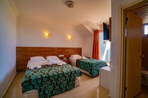 A hotel room with two beds, a wooden headboard, a flat-screen TV, and a door to the right. - Prenses Sealine Beach Hotel (Serik)
