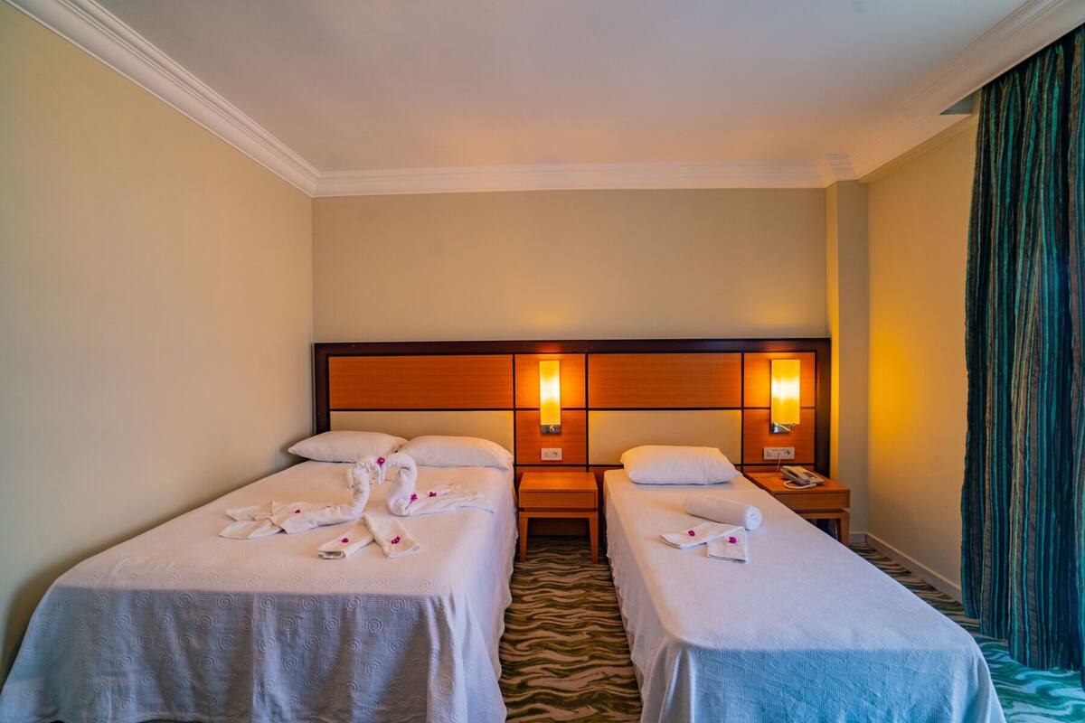 A hotel room with two single beds, a wooden headboard, bedside lamps, and a zebra-patterned carpet.