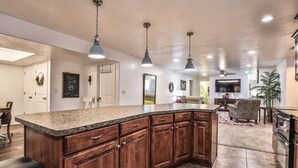 A spacious kitchen with granite countertops, wooden cabinets, and pendant lighting.