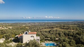 Una villa con piscina, rodeada de olivos y vistas al mar.