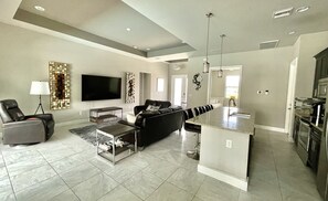 Relax and socialize in this spacious living area with a large flat-screen TV, comfortable seating, and a dining table.