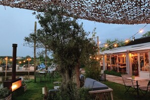 An outdoor patio area with seating, a fire pit, and string lights. - Holiday Home near Oosteruine Lake & North Sea (Noordwijkerhout)