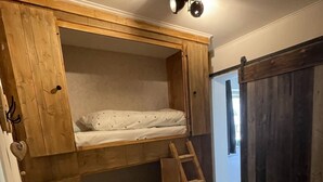 Una litera con escalera, paredes de madera y una lámpara en el techo.