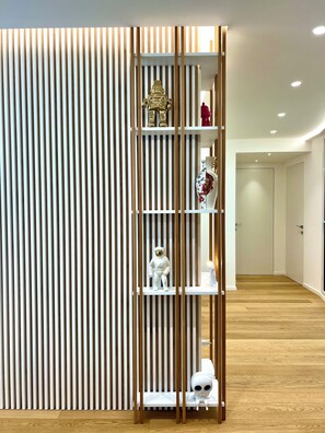Un intérieur moderne avec un mur composé de lambris en bois verticaux, une étagère blanche agrémentée d’objets décoratifs et un plancher en bois.