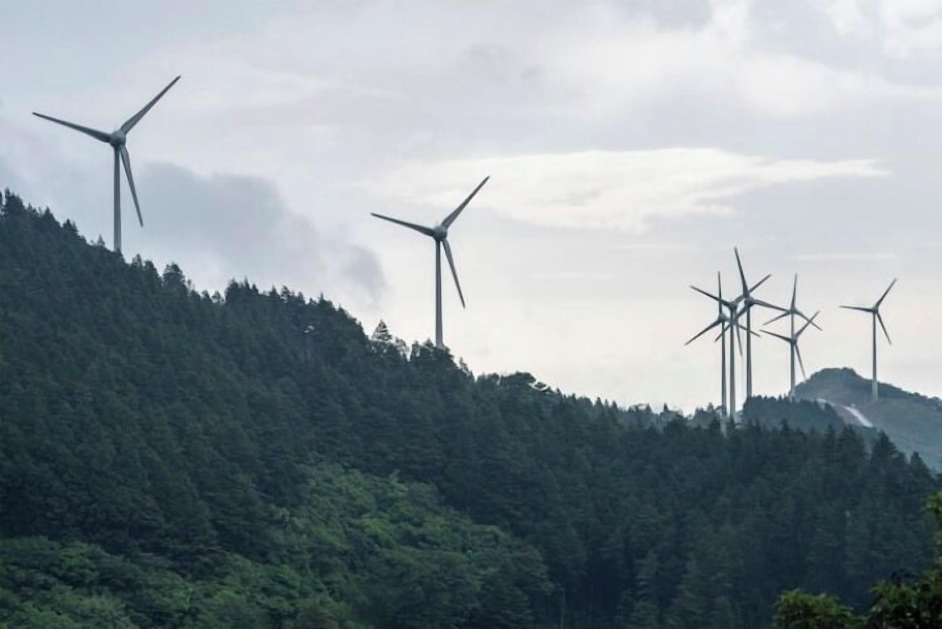 A landscape with multiple wind turbines on a hill.