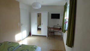 A room with a bed, a desk, a chair, a television, and a wardrobe. - Room with private bathroom in detached house (Königsfeld im Schwarzwald)