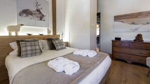 Ein Schlafzimmer mit einem Holz-Kopfteil, einem Bett mit weißer Bettwäsche, einer Holzkommode und zwei Bildern an den Wänden.