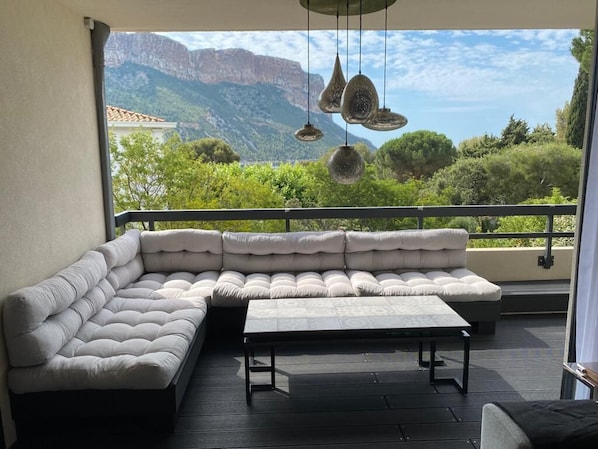 A modern outdoor seating area with a sectional sofa and a small table, overlooking a mountainous landscape. - Appartement Villa Cassis (Cassis)