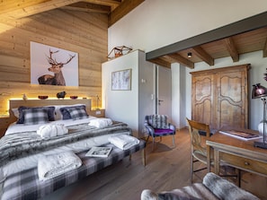 A bedroom with a bed, a chair, a desk, and a wardrobe.