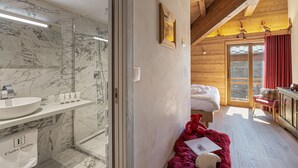 Une salle de bain avec un lavabo en marbre, une cabine de douche en verre et un plafond en bois.