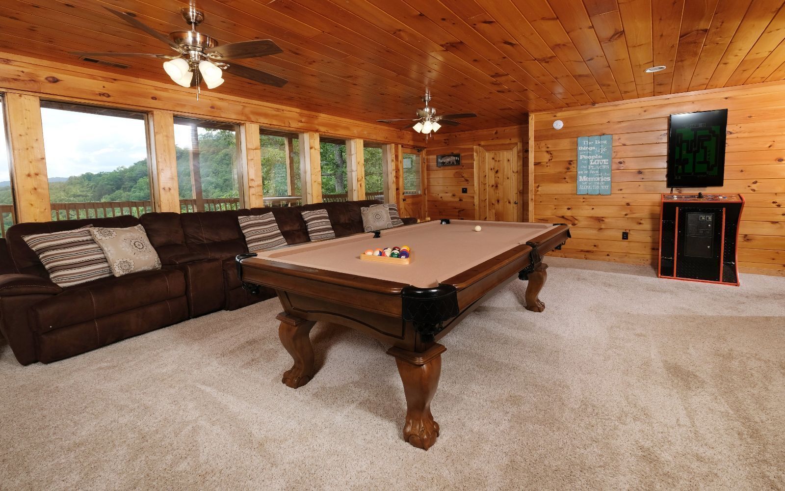 A wooden interior with a pool table, a sofa, and a television.