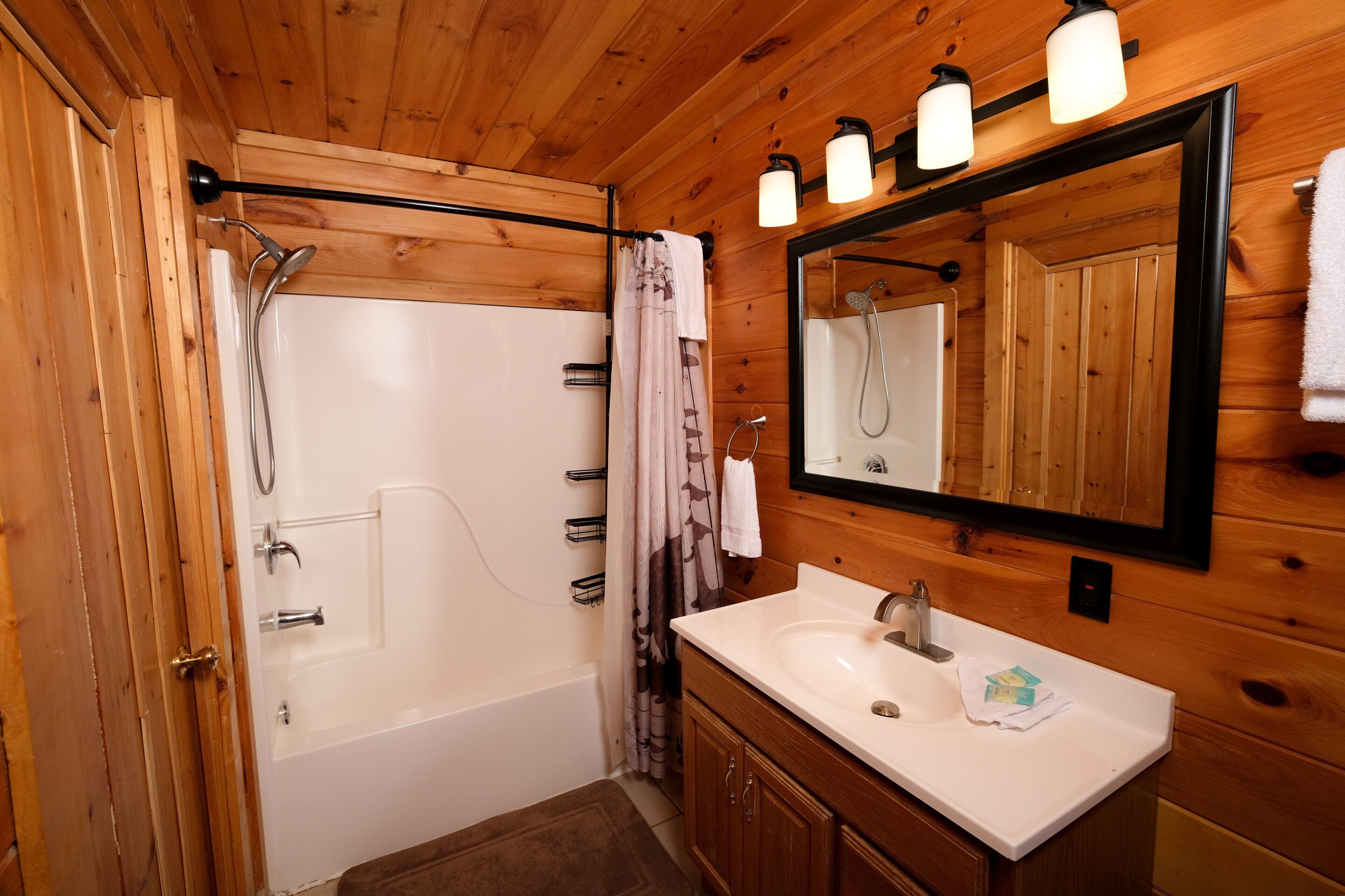 A wooden-paneled bathroom with a bathtub, a sink, and a mirror.