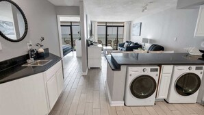 A modern kitchen with a built-in washer and dryer, a large window, and a balcony with outdoor seating. - Ocean Park Private, Luxurious & Incredible Views (Myrtle Beach)