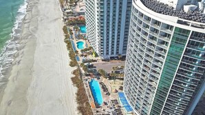 Un hôtel de grande hauteur doté d’une piscine, d’un accès à la plage et de plusieurs balcons.