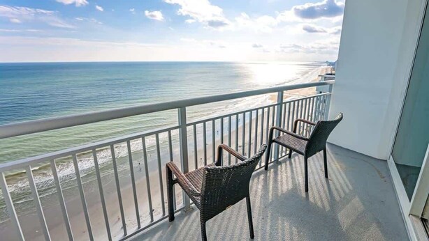 A balcony with two wicker chairs overlooking a beach. - New Top Floor Direct Oceanfront with Amazing View! (Myrtle Beach)