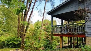 Een huis met een overdekte veranda, omgeven door weelderige begroeiing en bomen.