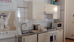 Een moderne keuken met witte kastjes, een gasfornuis, een magnetron en een spoelbak.