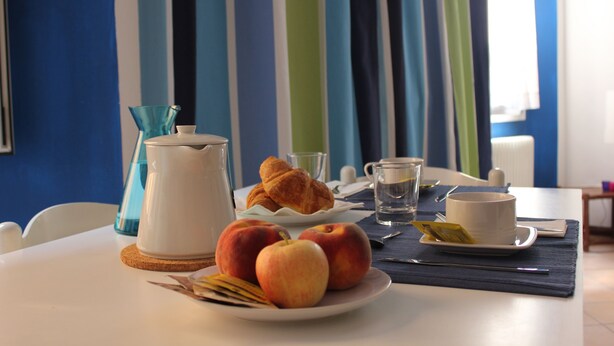 Een ontbijttafel met croissants, appels, een kop en een karaf.