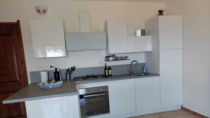 A modern kitchen with white cabinetry, a gas stove, a built-in oven, and a sink. - Sea view, Pleasant house in the heart of olive groves in the countryside (Murta Maria)