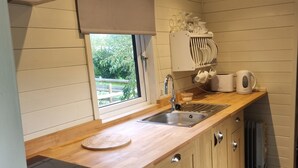 Une cuisine moderne avec des meubles en bois, un four encastré, un évier et une fenêtre donnant sur un paysage verdoyant.