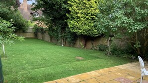 A well-maintained garden with a paved patio area, a wooden fence, and a variety of greenery. - Beautiful big Independent Furnished Bungalow (High Wycombe)