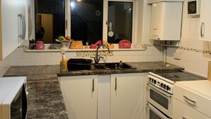 A compact kitchen with white cabinets, a built-in oven, a sink, and a window above the sink. - Beautiful big Independent Furnished Bungalow (High Wycombe)