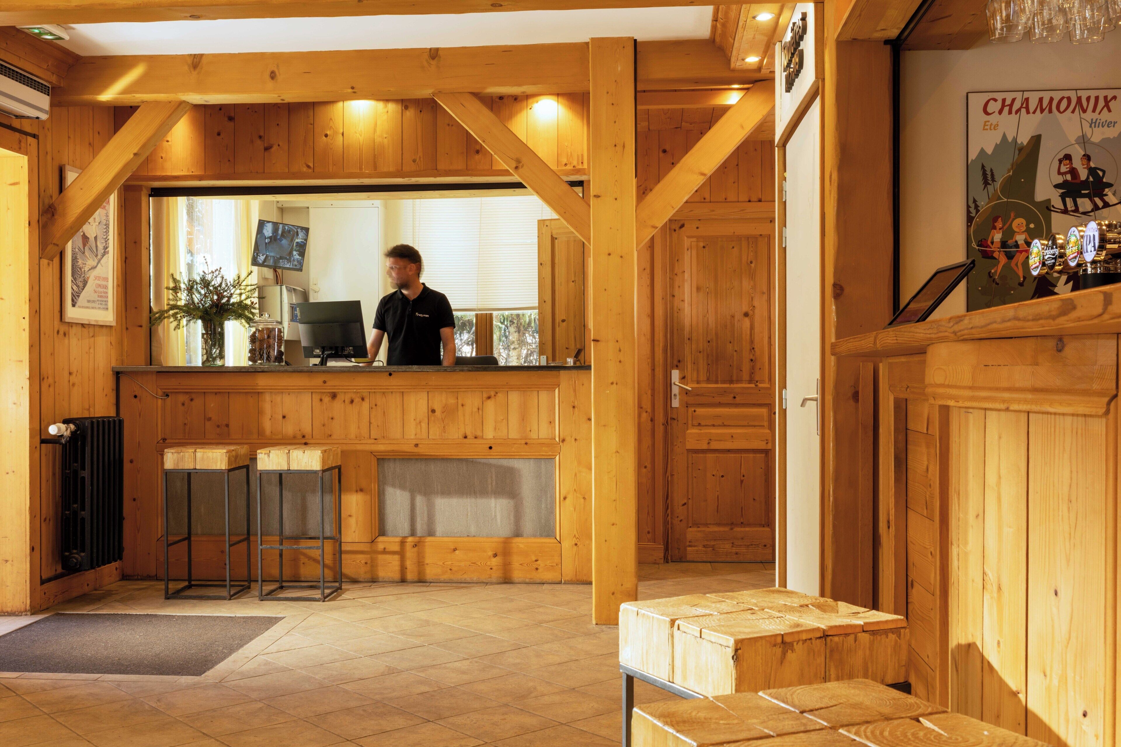 A wooden interior with a reception desk, a computer, and a poster on the wall.